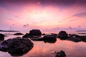 vista do mar com pedra ao nascer do sol.