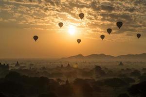 balões de ar quente sobrevoam as planícies de bagan durante o nascer do sol da manhã em mianmar. foto