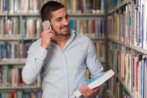 estudante do sexo masculino falando ao telefone na biblioteca