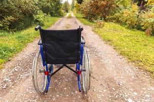 cadeira de rodas vazia em pé na estrada à espera de serviços ao paciente. cadeira de rodas para pessoas com deficiência estacionada ao ar livre. acessível para pessoa com deficiência. conceito médico de cuidados de saúde. foto