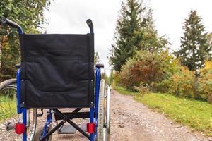 cadeira de rodas vazia em pé na estrada à espera de serviços ao paciente. cadeira de rodas para pessoas com deficiência estacionada ao ar livre. acessível para pessoa com deficiência. conceito médico de cuidados de saúde. foto