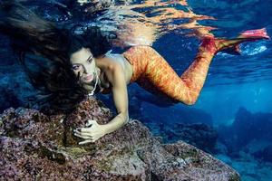 sereia nadando debaixo d'água no mar azul profundo foto