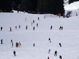 muitos esquiadores esquiando nas montanhas de neve do vale das dolomitas gardena foto