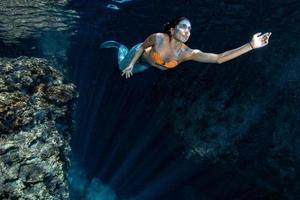 sereia nadando debaixo d'água no mar azul profundo foto