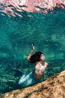 sereia nadando debaixo d'água no mar azul profundo foto