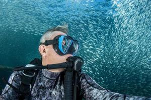 mergulhador selfie subaquático dentro da bola de isca de sardinha foto