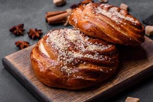 deliciosos pães de canela crocantes frescos polvilhados com migalhas de coco em uma tábua de madeira foto