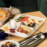 um prato de café da manhã e uma cesta de pão em uma mesa de madeira