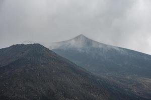 fumaça emitindo do monte etna no céu em meio a paisagem vulcânica foto