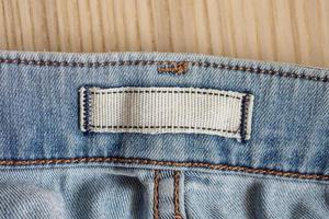 etiqueta de roupas em branco no fundo de jeans azul foto