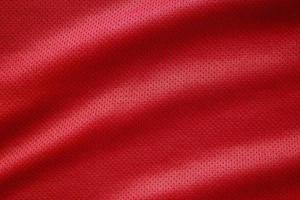 camisa de futebol de roupas esportivas de tecido vermelho com fundo de textura de malha de ar foto