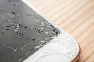vidro quebrado da tela do celular em fundo de madeira foto