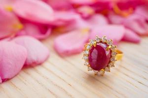 anel de rubi vermelho de joias com lindo fundo de pétalas de rosa rosa close-up foto