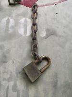 um velho cadeado enferrujado fechado em uma corrente maciça em fundo de ferro foto