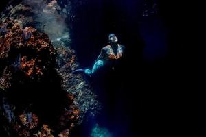 sereia nadando debaixo d'água no mar azul profundo foto