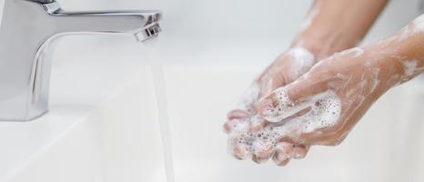 higiene. mãos de limpeza. lavar as mãos com sabão sob a torneira com água paga. foto