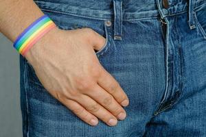 mão masculina com pulseira de arco-íris vestindo jeans. liberdade e conceito lgbt foto