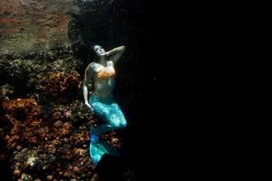 bela sereia nadando debaixo d'água no mar azul profundo foto