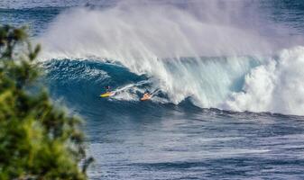 dois surfistas na água enquanto as ondas quebram nas mandíbulas foto