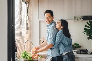 casal asiático lavar legumes na pia da cozinha foto