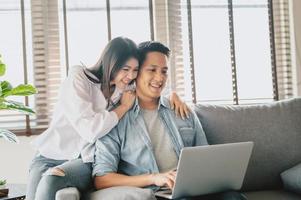 casal asiático usando laptop no sofá em casa foto