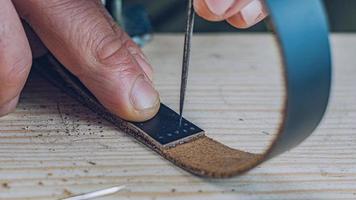 artesão fazendo uma pulseira de couro preta