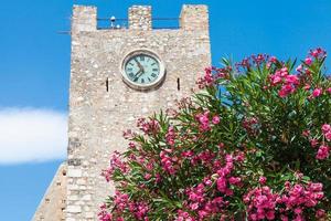 árvore de oleandro e torre do relógio medieval em taormina foto