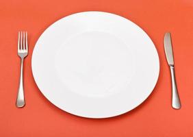 vista acima do prato de porcelana, garfo, faca no vermelho foto