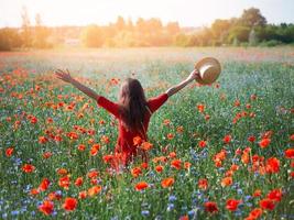 jovem mulher bonita com os braços erguidos no campo de papoilas de primavera