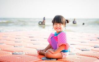 menina asiática sorrindo na praia foto