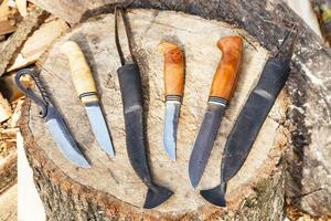 facas feitas à mão no toco de árvore foto