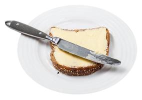 pão de grãos e manteiga com faca de mesa no prato foto
