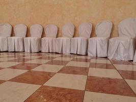 muitas cadeiras cobertas brancas de casamento foto