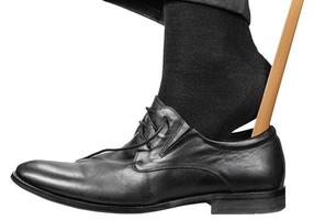 homem calça sapato preto com calçadeira isolada foto