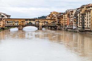 ponte vecchio sobre o rio arno e casas no outono foto