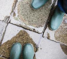 pernas em botas de borracha verde na poça foto