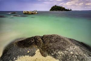 litoral arenoso com pedra grande foto