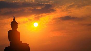 silhueta da estátua de Buda ao pôr do sol foto