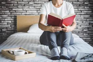 jovem, desfrutando de um livro na cama foto