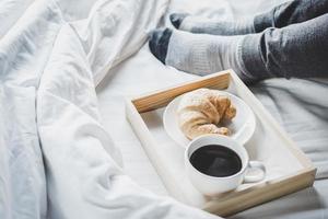 jovem mulher na cama com café da manhã foto