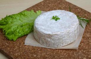 queijo camembert na tábua de madeira e fundo de madeira foto