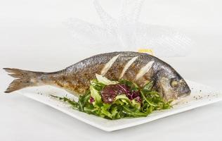 peixe dourado com salada na chapa branca. tiro de estúdio foto