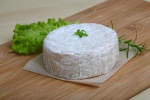 queijo camembert na tábua de madeira e fundo de madeira foto