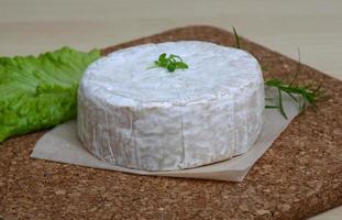 queijo camembert na tábua de madeira e fundo de madeira foto