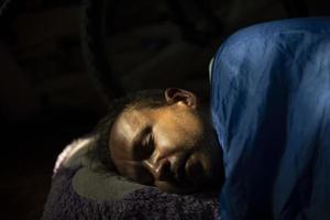 cara dorme de manhã. homem dorme profundamente sob o cobertor. jovem encontra-se na luz solar. foto