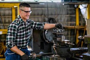 um engenheiro usando óculos de proteção trabalha em uma máquina