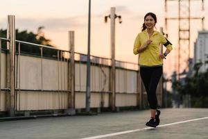 jovem atleta asiática correndo em uma ponte de passagem ao ar livre foto