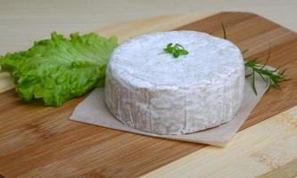 queijo camembert na tábua de madeira e fundo de madeira foto