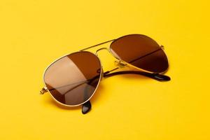 óculos de sol aviador em fundo amarelo foto