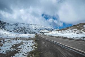 uma estrada em meio a montanhas cobertas de neve foto